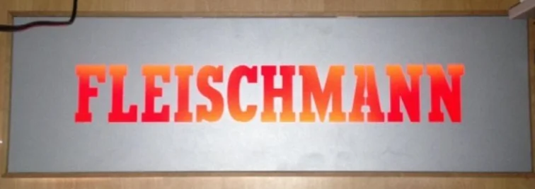 Fleischmann-Schriftzug in rot-orangem Farbverlauf auf grauer Tafel, beleuchtet