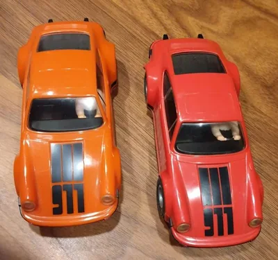 Bild eines Fleischmann-Testmodells: links das Serienmodell Porsche Carrera 911 in Orange mit Aufdruck, rechts das Vorserienmodell in Rot mit Aufdruck